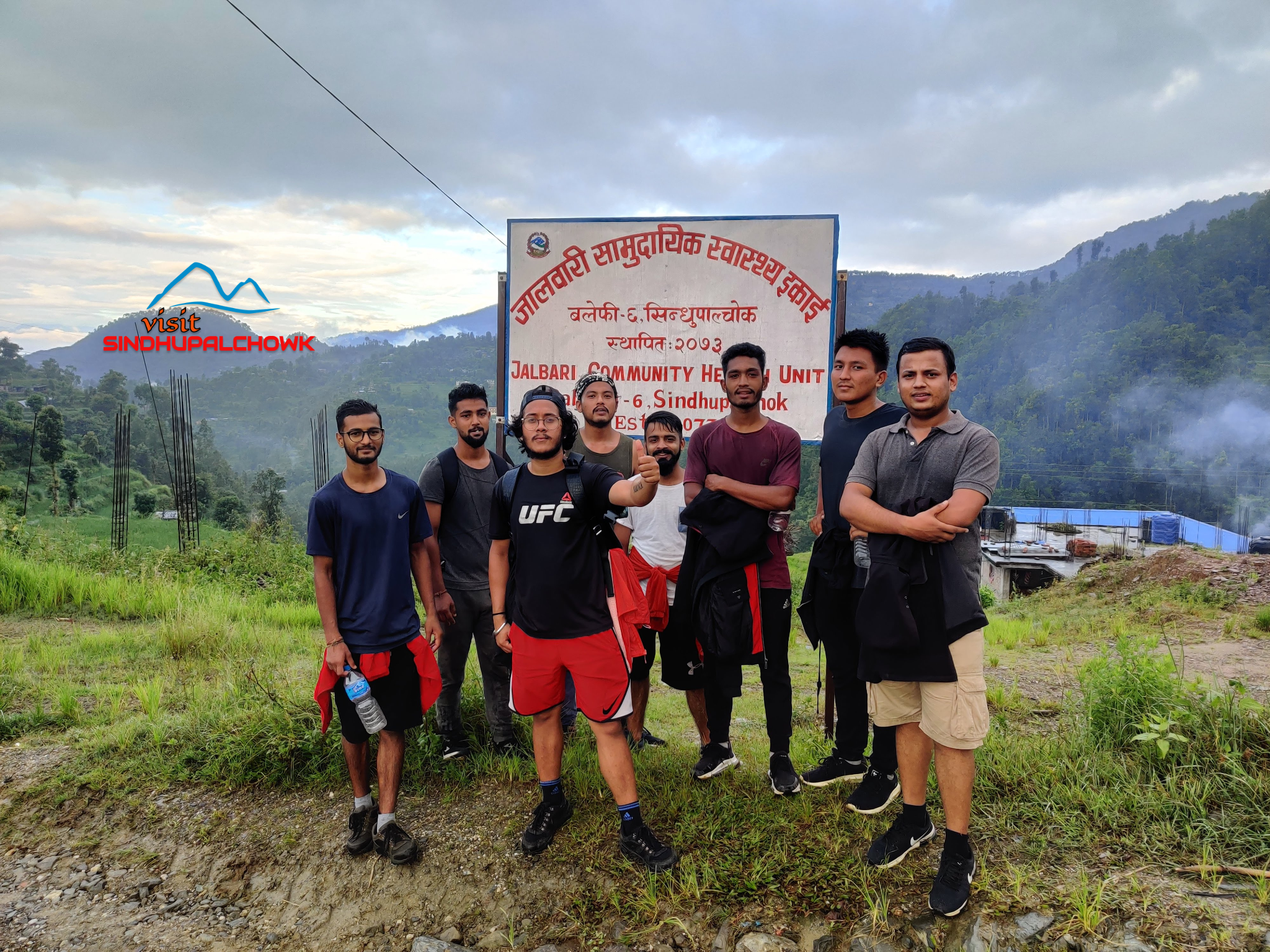 Local hikers standing in front of the Jalbari Community Health Unit board during their hike to Ghunde.